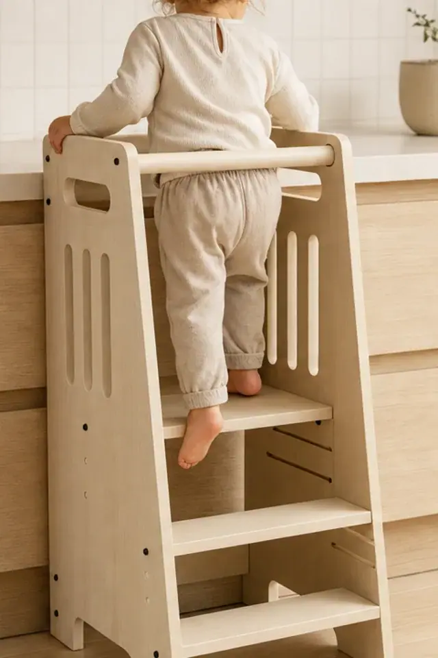 A child standing in the tower at the kitchen counter