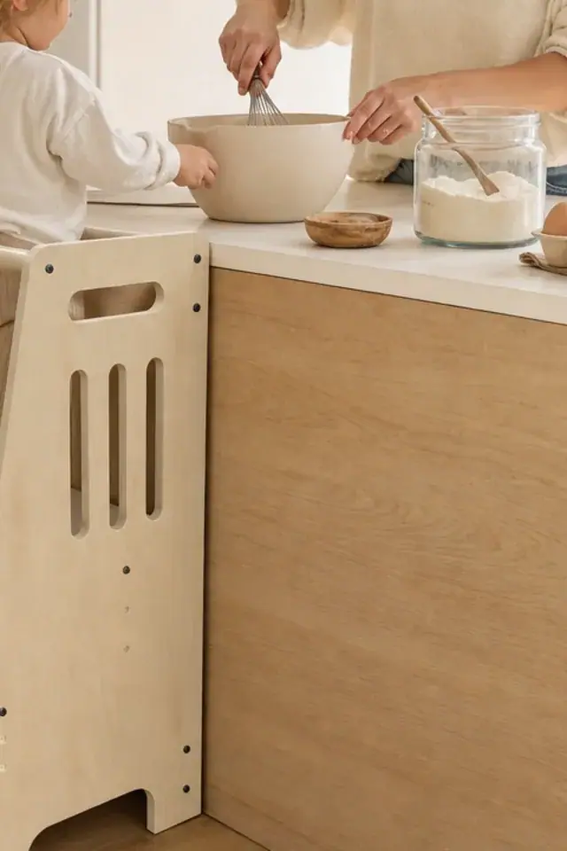 A mother mixing a bowl at the counter beside the tower