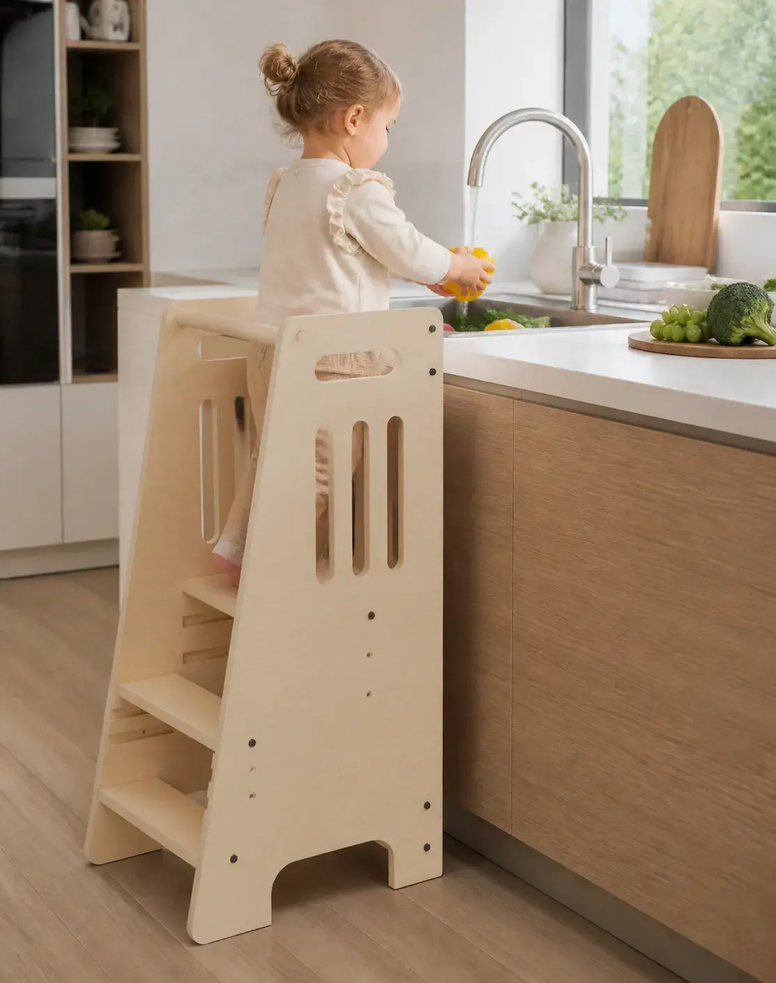 A child in the tower washing a yellow pepper at the kitchen sink