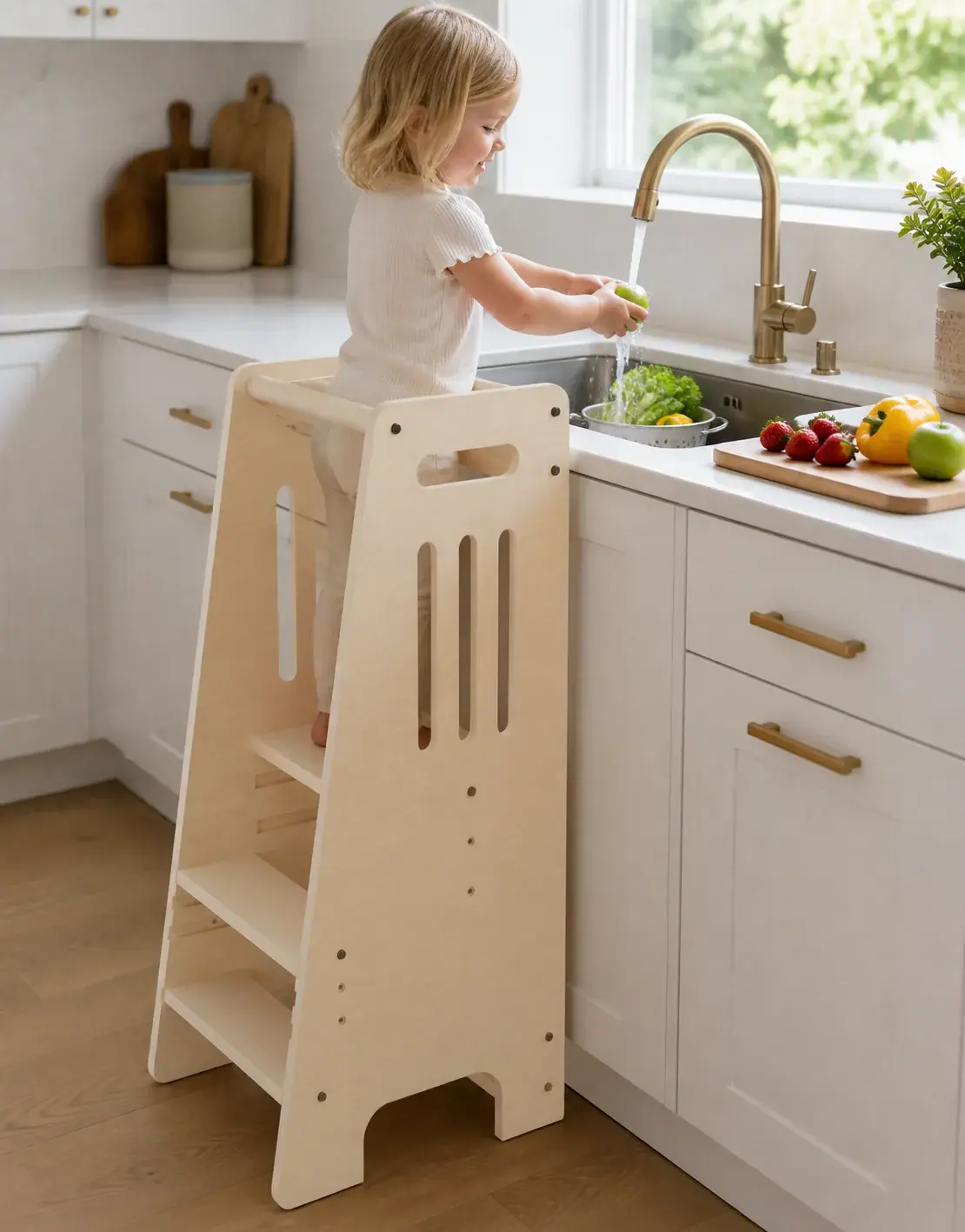 A child in the tower rinsing an apple under the kitchen faucet