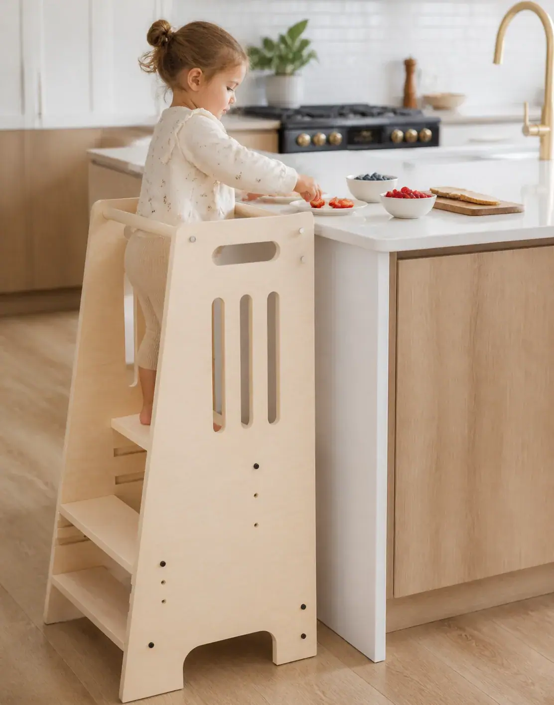 A child in the tower reaching for strawberries to prepare a snack